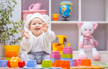 baby girl playing with colourful building blocks at home or kindergarten