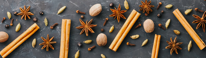 Collection of spices for mulled wine and pastry on the wooden table. Cinnamon sticks, cardamom, cloves, allspice, star anise