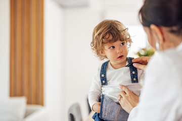 Portrait of a cute toddler looking at the female doctor, while g