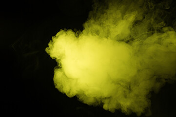 Colorful smoke close-up on a black background. Yellow cloud of smoke.