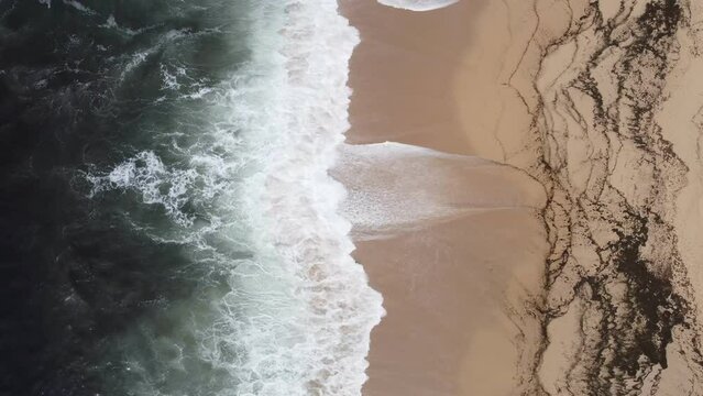 Arial shot of a beach and ocean waves.