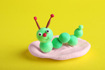 Colorful caterpillar made from play dough on yellow background, closeup