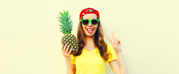 Summer portrait of happy smiling woman with pineapple wearing sunglasses, red baseball cap on white background