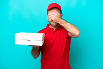 Pizza delivery man with work uniform picking up pizza boxes isolated on blue background covering...