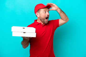 Pizza delivery man with work uniform picking up pizza boxes isolated on blue background doing...