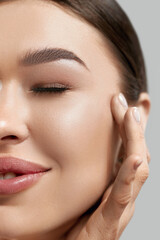 Obraz premium Closeup happy young woman applying cream to her face Skincare and cosmetics concept. Cosmetics. Woman face skin care.Natural makeup, touching face.