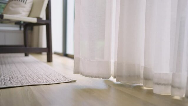 close up white sheer curtain with sun light with shadow shade on wooden floor home interior design concept,cozy home morning light with sun through white curtain window peaceful and clam moment