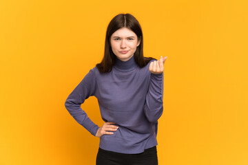 Young Ukrainian girl isolated on yellow background making Italian gesture