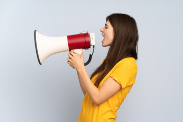 Young Ukrainian girl isolated on white background shouting through a megaphone to announce something in lateral position