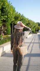 A girl with beautiful long dreadlocks and jewelry walks on the city. Hippie girl in boho style view from the back. Boho style, gypsy, street honor, travel