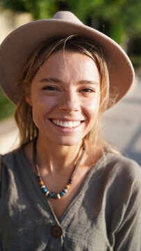 Close portrait of a smiling hippie girl. A charming girl with freckles in a hat smiles and laughs merrily. Bright and beautiful smile