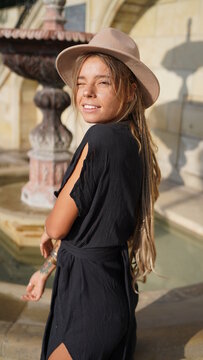 Portrait of a smiling girl with dreadlocks. Bohemian woman in boho style holding a hat. A charming girl in black kimono in a hat posing. Bright and beautiful smile, street style.