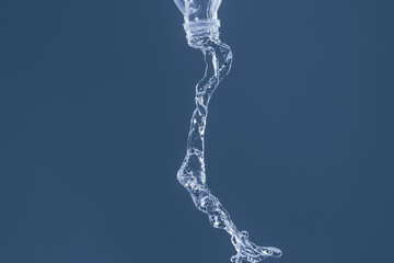 Splash of water from a bottle on a blue background. Reflection on the surface of the water.