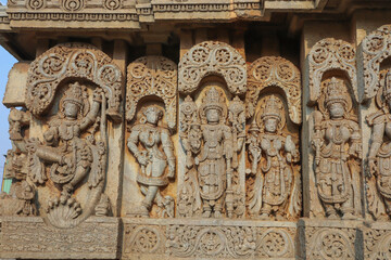 The exterior wall of an old Hoysala Shiva temple with artistic sculptures of mythological deities at Hosaholalu town in India.

