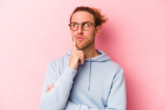 Young caucasian man isolated on pink background contemplating, planning a strategy, thinking about the way of a business.