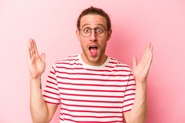Young caucasian man isolated on pink background receiving a pleasant surprise, excited and raising hands.
