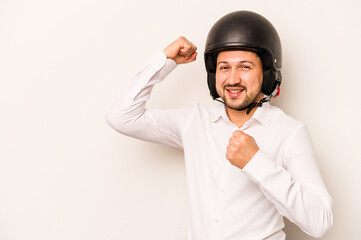 Hispanic business man going to work with motorcycle isolated on white background raising fist after a victory, winner concept.