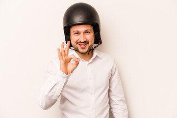 Hispanic business man going to work with motorcycle isolated on white background cheerful and confident showing ok gesture.