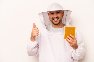 Hispanic beekeeper man holding honey isolated on white background smiling and raising thumb up