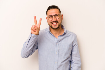 Young hispanic man isolated on white background joyful and carefree showing a peace symbol with fingers.