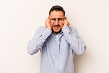 Young hispanic man isolated on white background covering ears with hands.