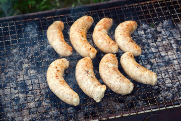 Grilled sausages on grill. BBQ grill with sausages. Delicious juicy meat sausags, cooking bratwursts, cooking on charcoal, smoky grill.