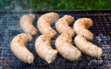 Chiken sausages cook on grill. Barbeque grill with sausages. Juicy sausages roasted on grate, cooking on charcoal and grill.