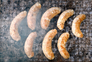 Sausage grilling, view from above on grilled sausages on grate closeup, homemade chicken sausages grilling on barbecue.