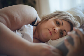 Depressed lonely fat woman lying in bed at home and thinking.
