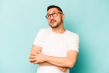 Young hispanic man isolated on blue background dreaming of achieving goals and purposes