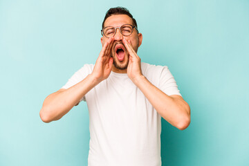 Young hispanic man isolated on blue background shouting excited to front.