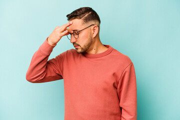 Young hispanic man isolated on blue background having a head ache, touching front of the face.