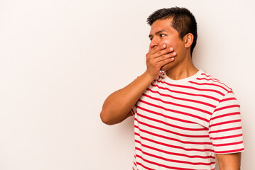 Young hispanic man isolated on white background thoughtful looking to a copy space covering mouth with hand.