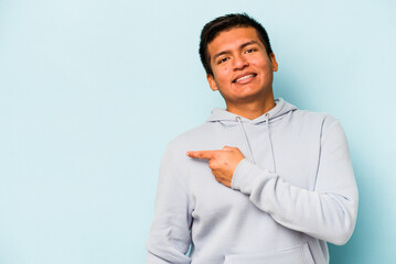 Young hispanic man isolated on blue background smiling and pointing aside, showing something at blank space.