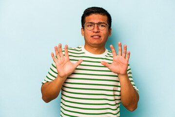 Young hispanic man isolated on blue background rejecting someone showing a gesture of disgust.