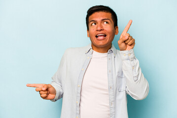 Young hispanic man isolated on blue background pointing to different copy spaces, choosing one of them, showing with finger.