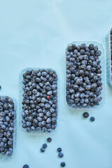 Flat lay of fresh organic juicy blueberries in a box on blue background, top view, copy space. Concept of healthy and dieting eating , antioxidant, vitamin, summer food.