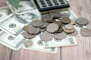 Money $100 dollar bills and coins and calculator piles on the wooden table as background shows the...