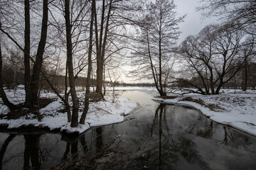 Spring landscape with a river. Snow melts in March. Evening in early spring.