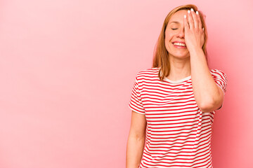 Young caucasian woman isolated on pink background laughing happy, carefree, natural emotion.