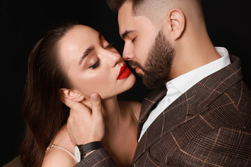 Handsome bearded man with sexy lady on black background, closeup