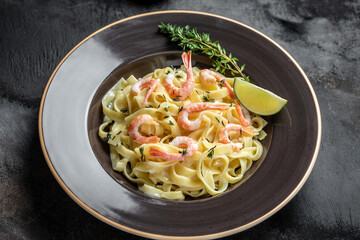 Pasta Tagliatelle with grilled shrimps, bechamel sauce and thyme, fettuccine pasta. Italian food. Food recipe background. Close up