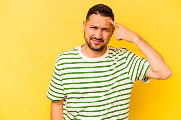 Young hispanic man isolated on yellow background showing a disappointment gesture with forefinger.