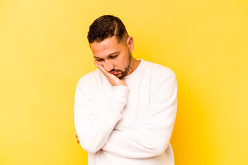 Young hispanic man isolated on yellow background who is bored, fatigued and need a relax day.