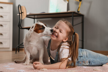 Cute little girl playing with her dog at home. Childhood pet