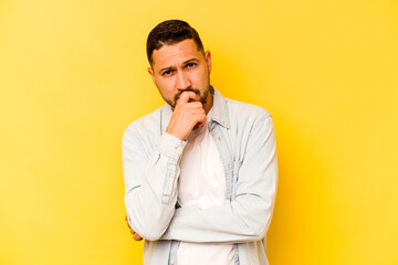 Young hispanic man isolated on yellow background thinking and looking up, being reflective, contemplating, having a fantasy.