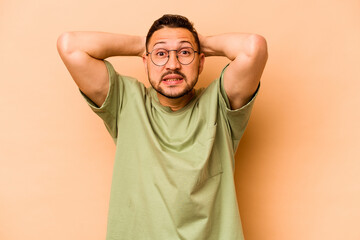 Young hispanic man isolated on beige background screaming with rage.