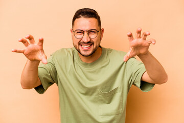 Young hispanic man isolated on beige background upset screaming with tense hands.