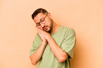 Young hispanic man isolated on beige background yawning showing a tired gesture covering mouth with hand.