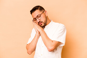 Young hispanic man isolated on beige background who is bored, fatigued and need a relax day.